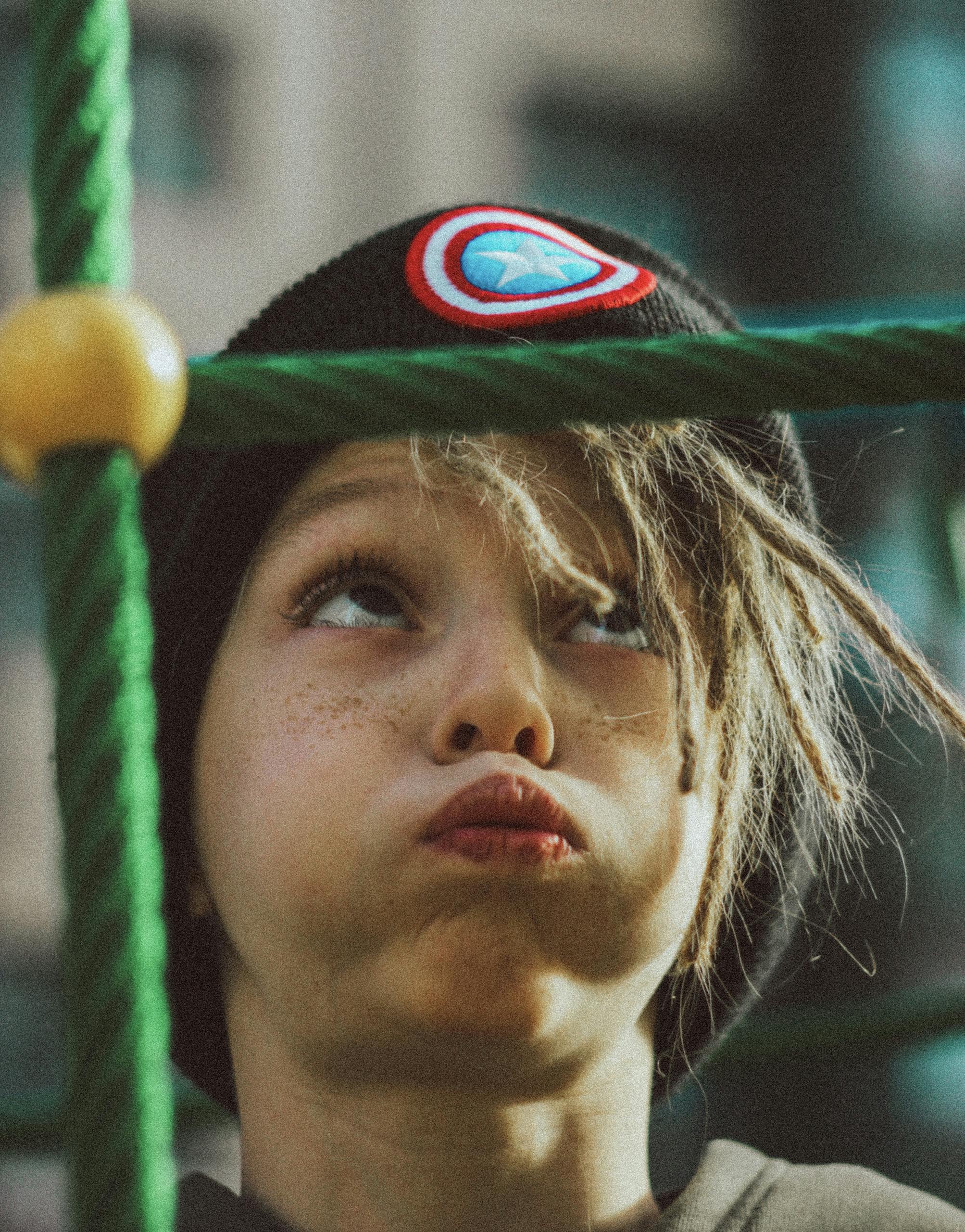 Close-up portrait of a child with freckles making a funny face on playground ropes.